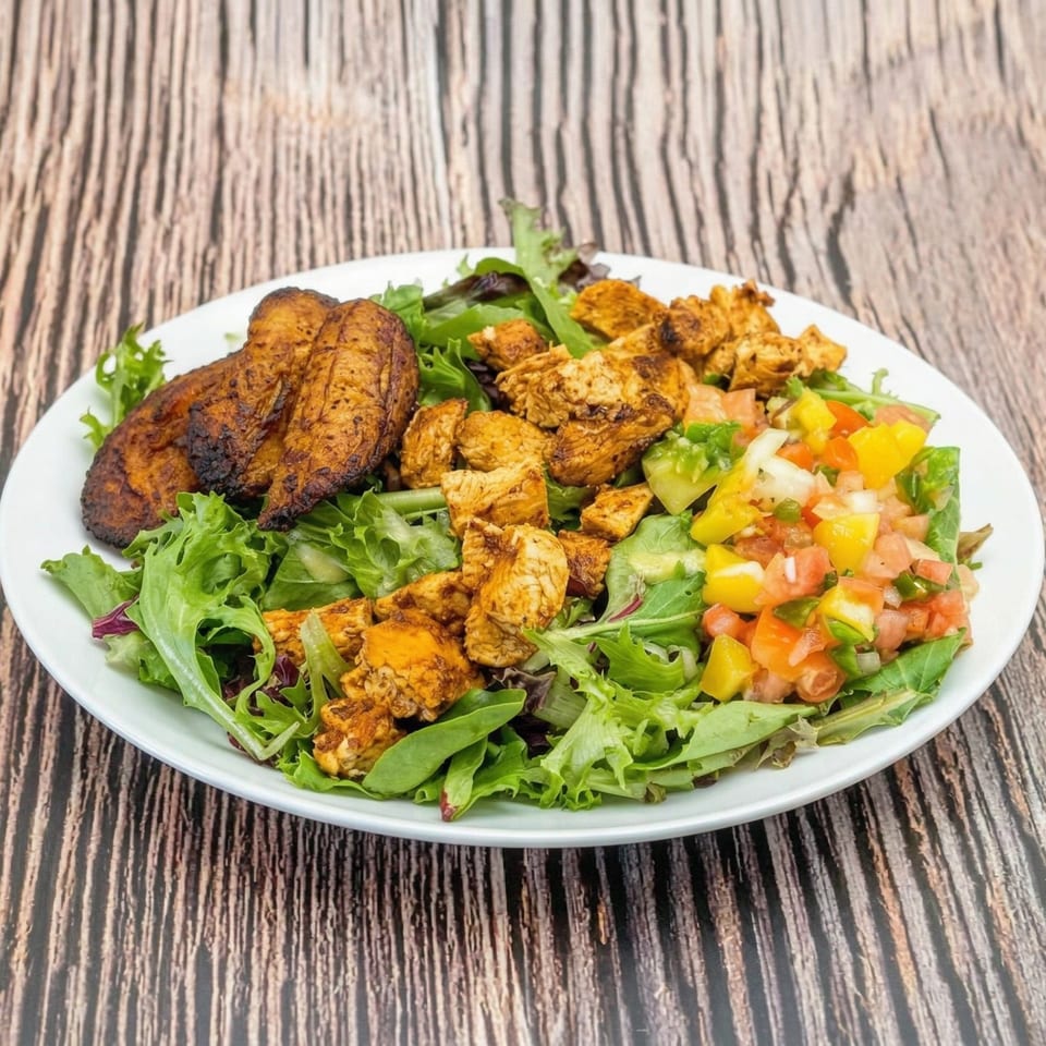A vibrant salad with mixed greens, seasoned chicken, fried plantains, and fresh mango salsa.